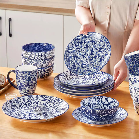 Selene 16-piece porcelain set in indigo patterns - showcasing plates - bowls - and mugs beautifully styled with vibrant meals on a rustic wooden table