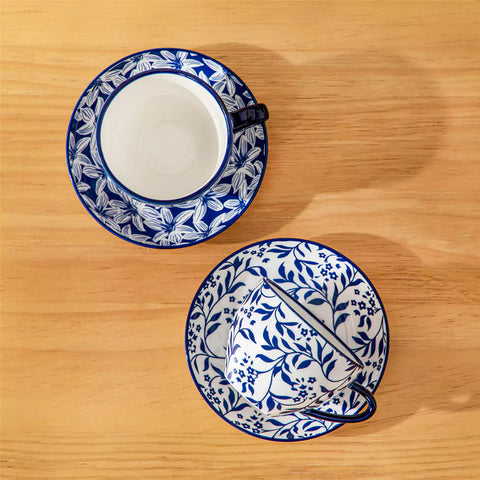 Set of 4 Selene indigo floral porcelain cups and saucers on a wooden table with coffee and pastries featuring blue and white Japanese style mix and match patterns