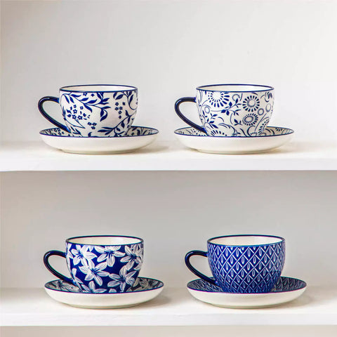 Set of 4 Selene indigo floral porcelain cups and saucers on a wooden table with coffee and pastries featuring blue and white Japanese style mix and match patterns