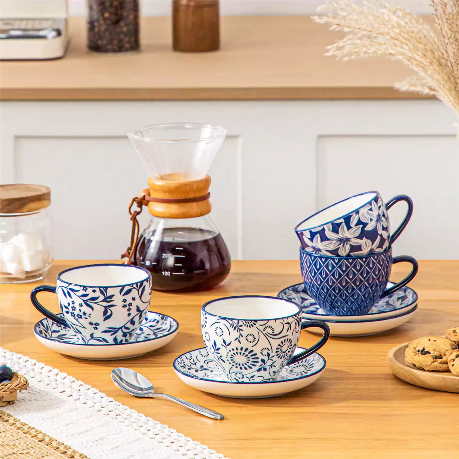 Set of 4 Selene indigo floral porcelain cups and saucers on a wooden table with coffee and pastries featuring blue and white Japanese style mix and match patterns