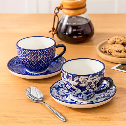 Set of 4 Selene indigo floral porcelain cups and saucers on a wooden table with coffee and pastries featuring blue and white Japanese style mix and match patterns