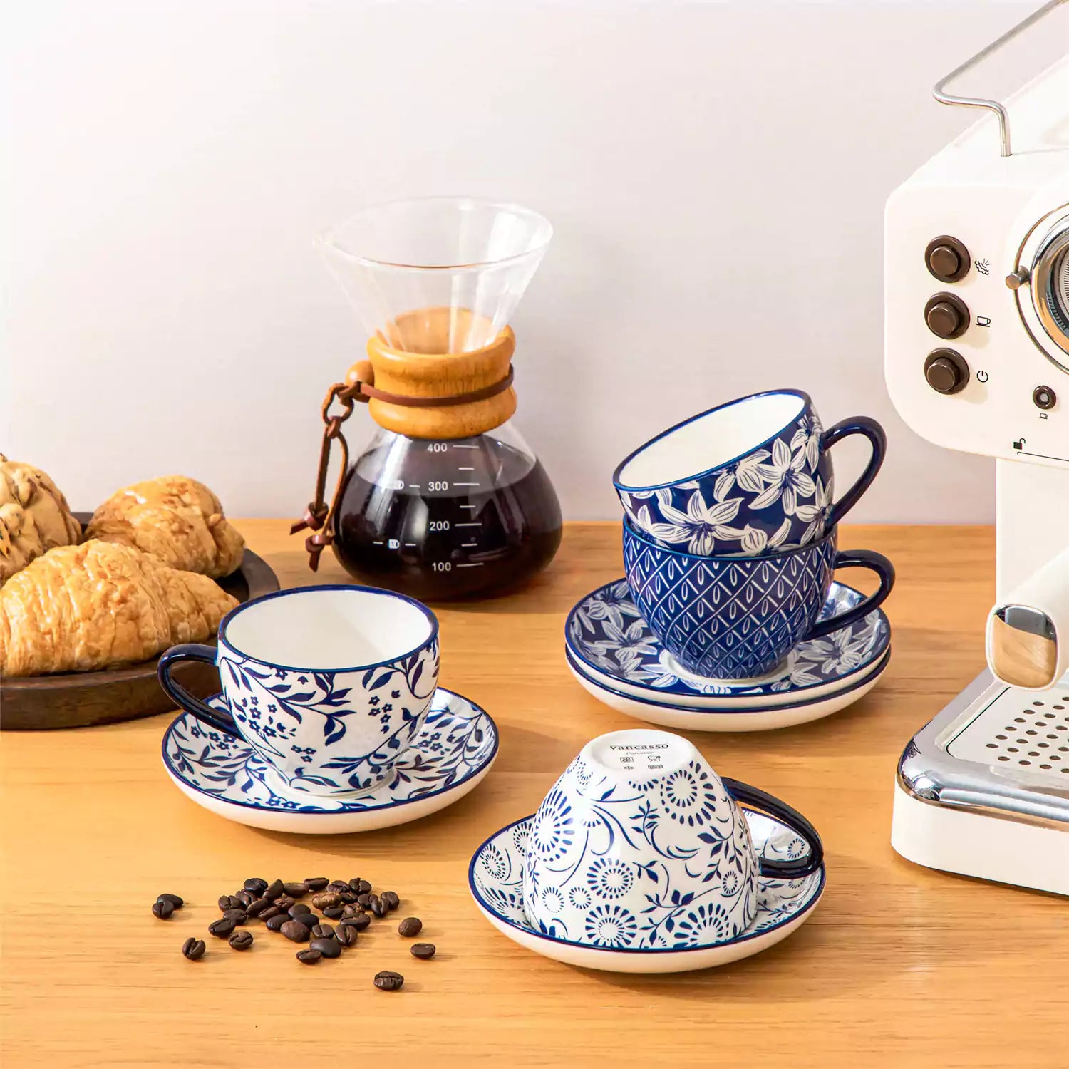 Set of 4 Selene indigo floral porcelain cups and saucers on a wooden table with coffee and pastries featuring blue and white Japanese style mix and match patterns