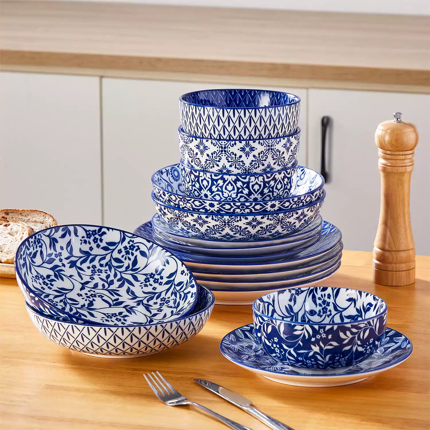 Selene 16-piece porcelain set with indigo floral and geometric patterns on plates - bowls - and mugs displayed on a dining table
