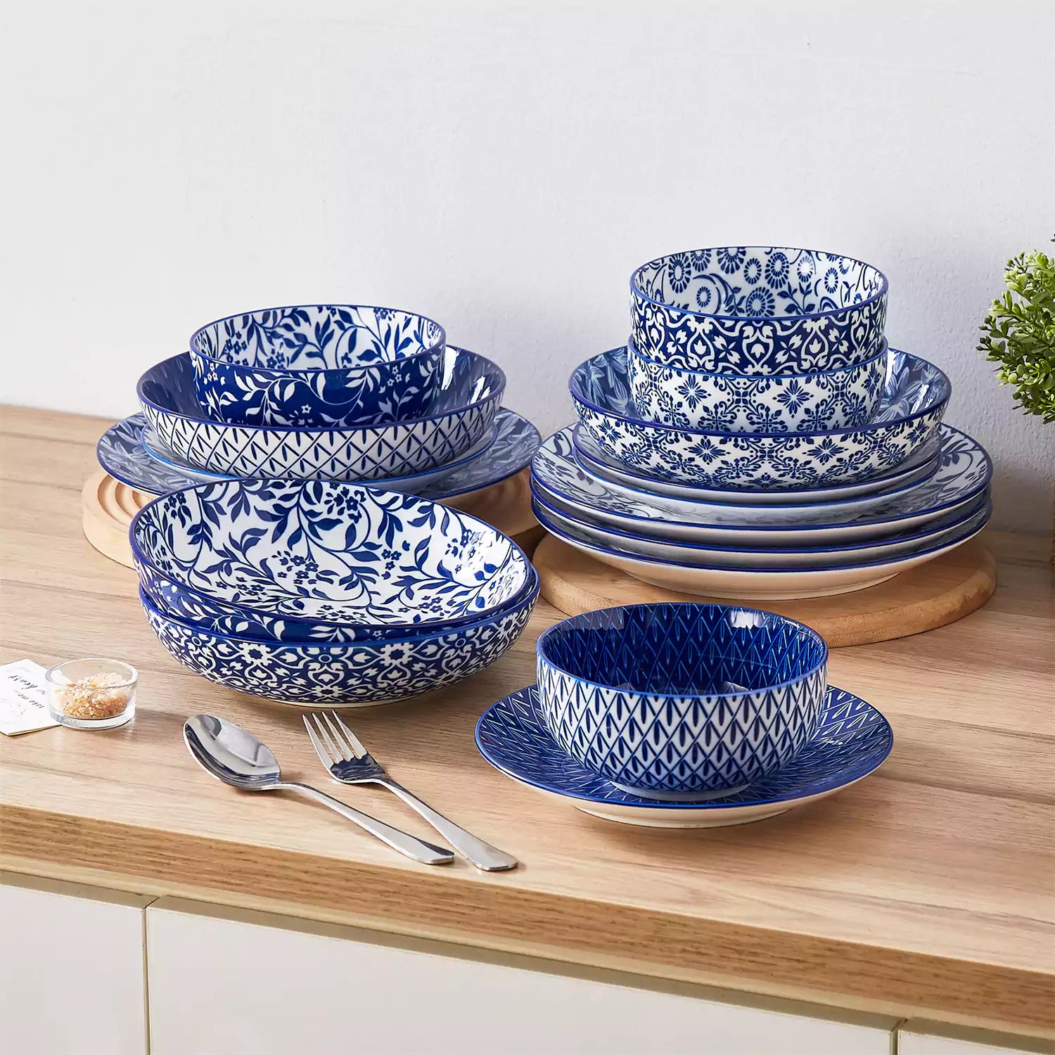 Selene 16-piece porcelain set with indigo floral and geometric patterns on plates - bowls - and mugs displayed on a dining table