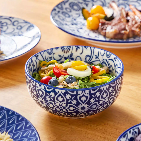 Selene 16-piece porcelain set with indigo floral and geometric patterns on plates - bowls - and mugs displayed on a dining table