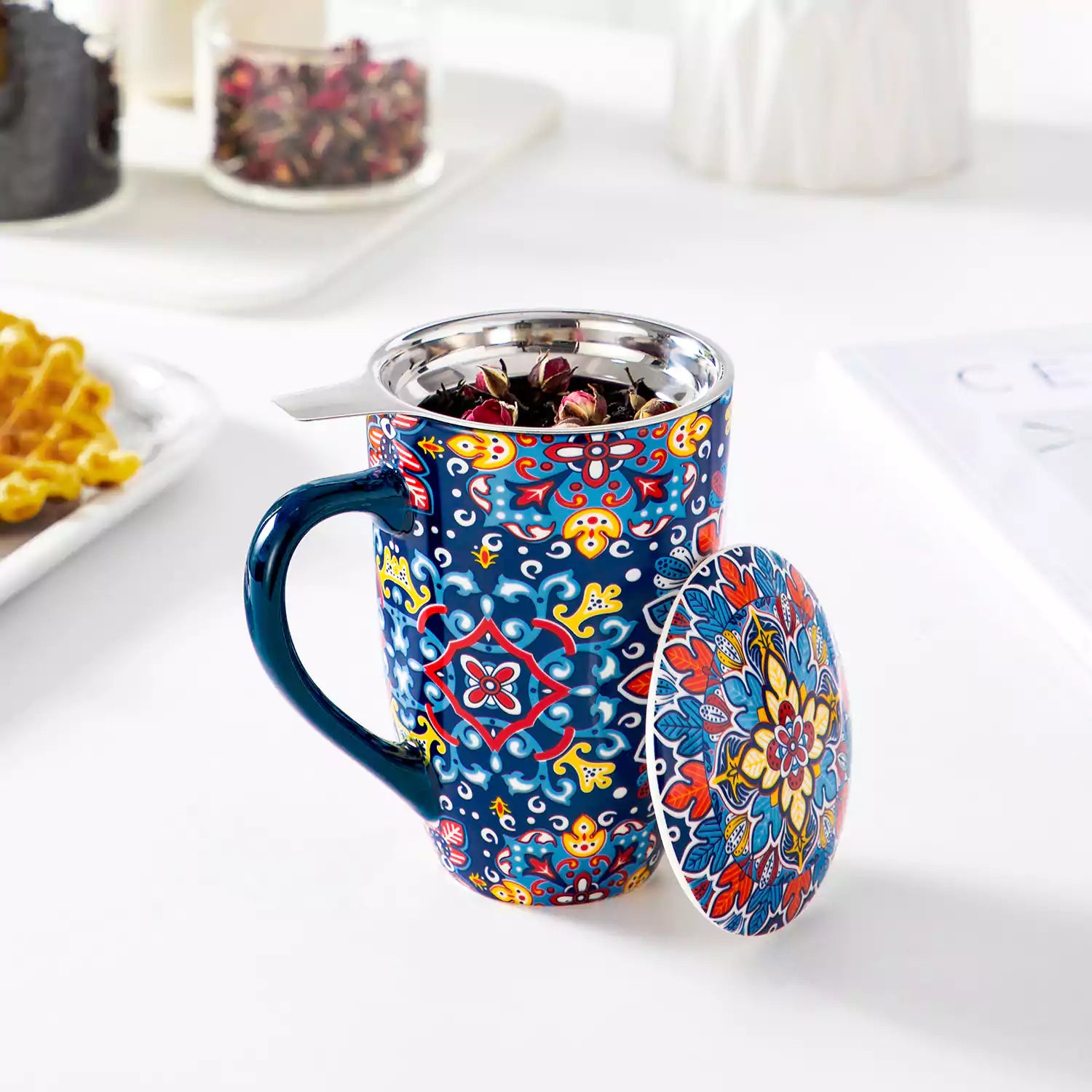 Simi tea mug with infuser and lid colorful navy blue boho chic ceramic coffee cup with spoon and loose tea leaves on white background