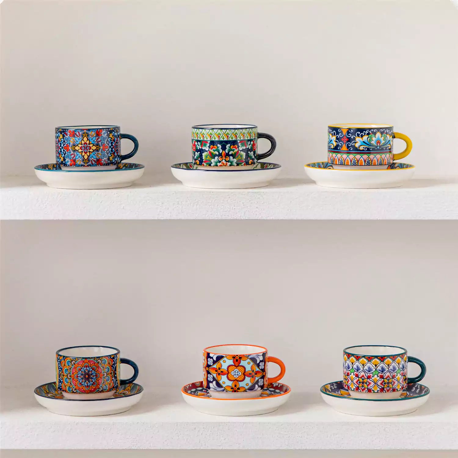 Simi 12 piece porcelain espresso set with 3oz cups and saucers in vibrant boho chic floral patterns on a black metal storage rack with a magazine and napkin on a wooden table