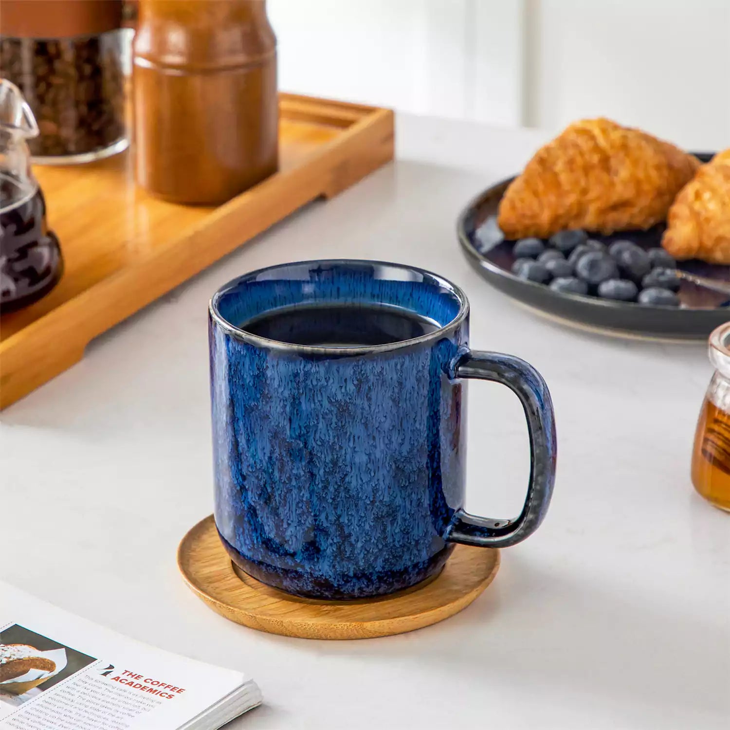 Starry gently curved blue mugs set of 6 displayed on a wooden table with a coffee maker and a plate of pastries