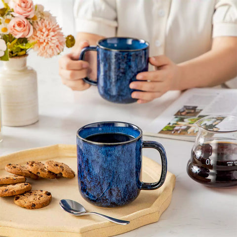 Starry gently curved blue mugs set of 6 displayed on a wooden table with a coffee maker and a plate of pastries