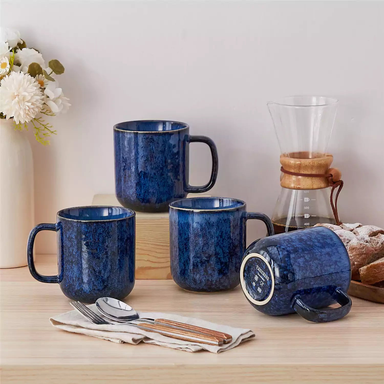 Four starry blue 16oz stoneware mugs with latte art on wooden table beside coffee brewing equipment