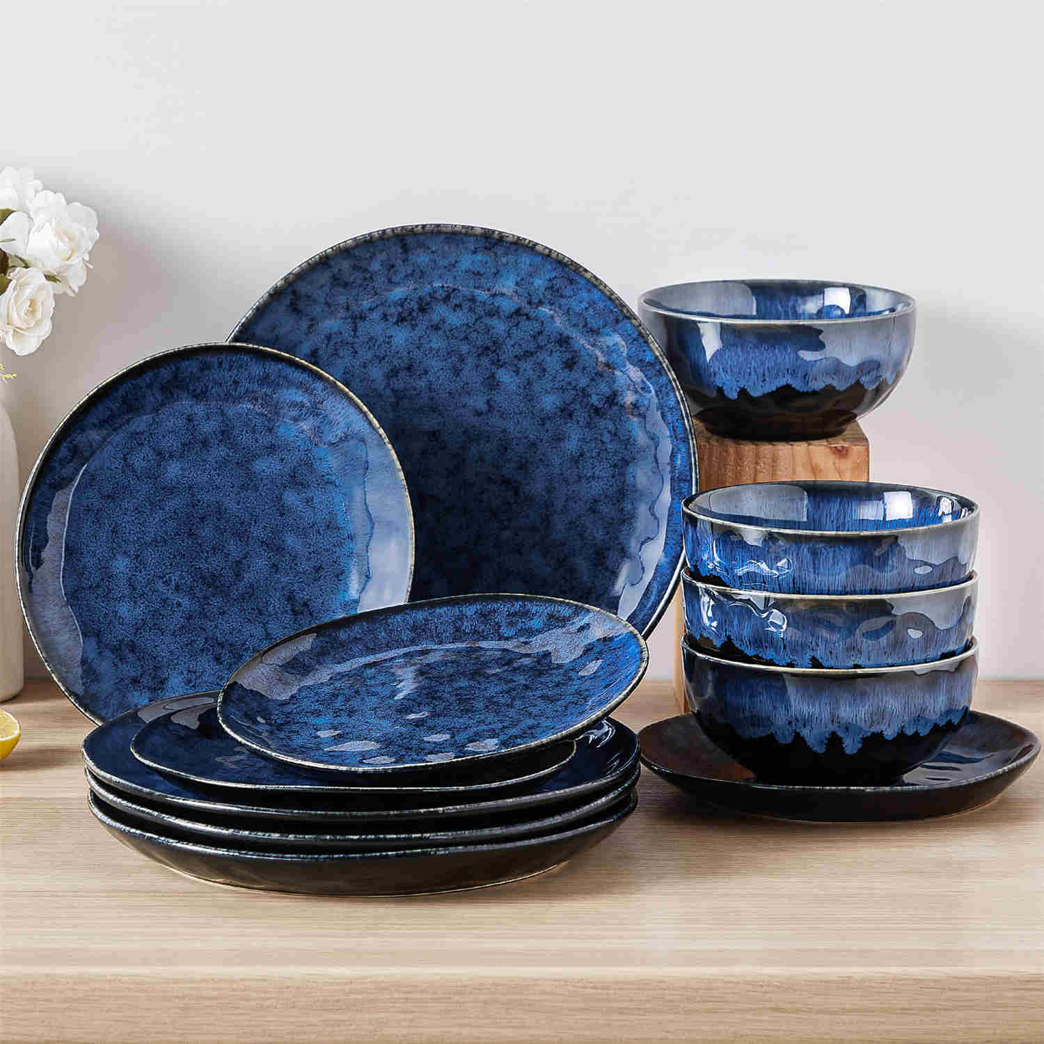 Starry 12-piece stoneware dinnerware set in blue on a light wooden table - styled with lamb chops - pastries - coffee pot - and lemon water for a cozy farmhouse breakfast scene