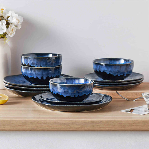 BlueaStarry 12-piece stoneware dinnerware set in blue on a light wooden table - styled with lamb chops - pastries - coffee pot - and lemon water for a cozy farmhouse breakfast scene
