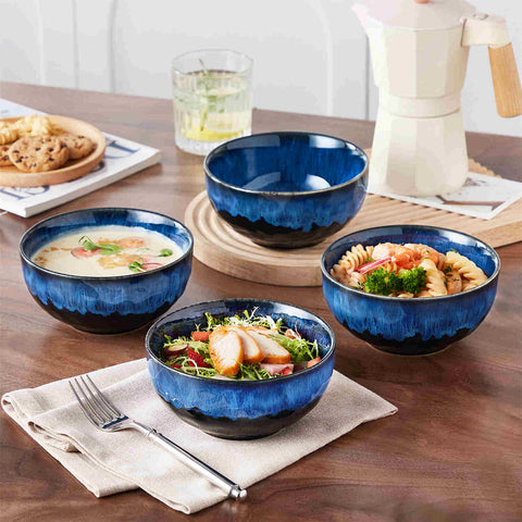 Starry reactive glaze cereal bowls in blue on a rustic wooden table - filled with creamy soup - pasta - and fresh fruit salad for a cozy - celestial dining vibe