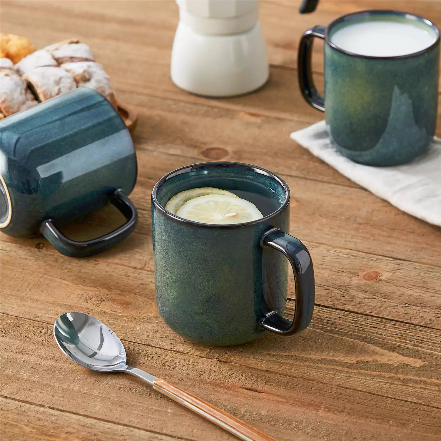 Four starry green 16oz stoneware mugs with latte art on wooden table beside coffee brewing equipment