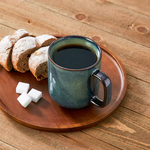 Four starry green 16oz stoneware mugs with latte art on wooden table beside coffee brewing equipment