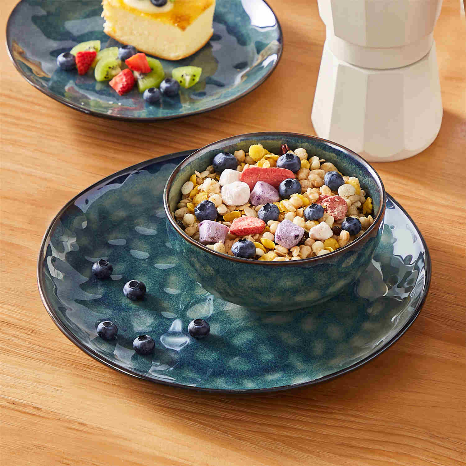 Starry 12-piece stoneware dinnerware set in green on a light wooden table - styled with lamb chops - pastries - coffee pot - and lemon water for a cozy farmhouse breakfast scene