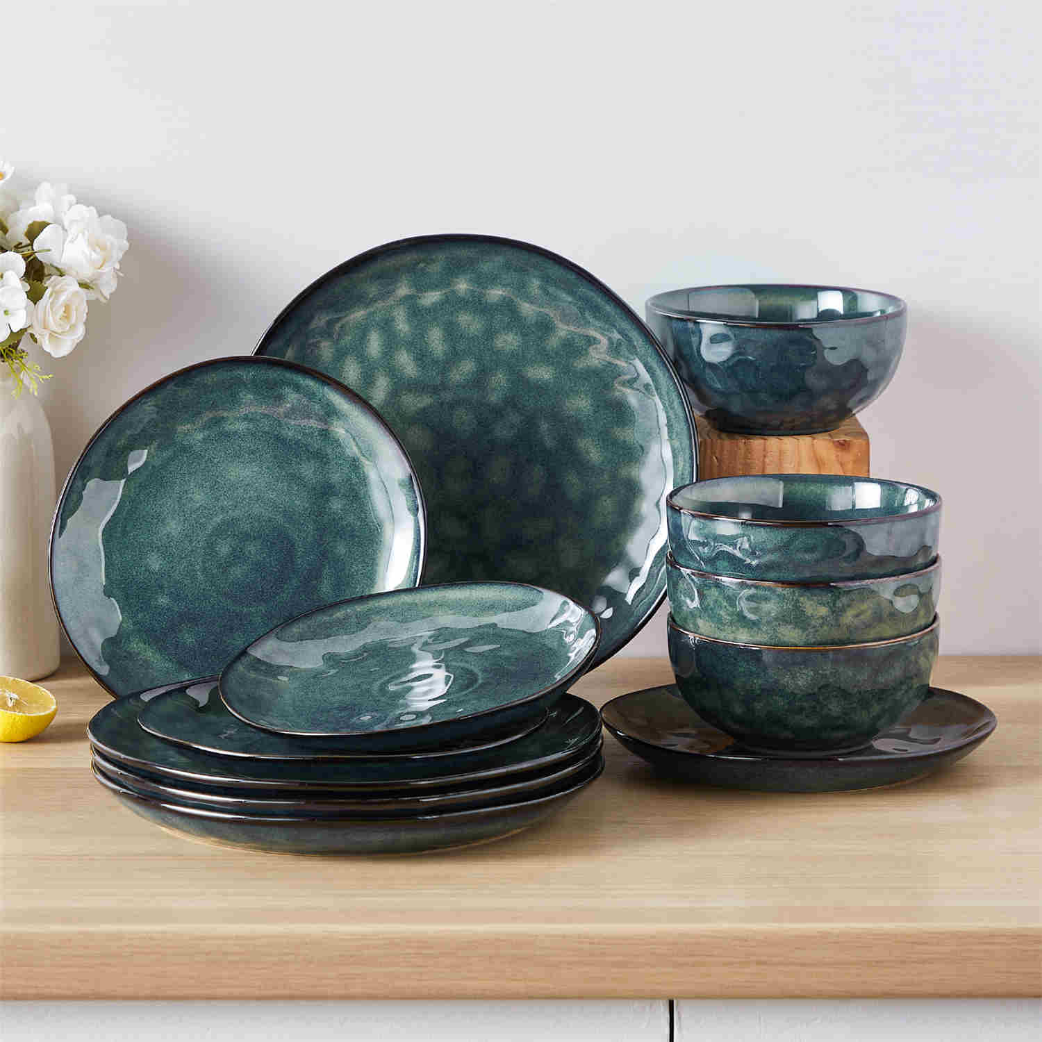 Starry 12-piece stoneware dinnerware set in green on a light wooden table - styled with lamb chops - pastries - coffee pot - and lemon water for a cozy farmhouse breakfast scene