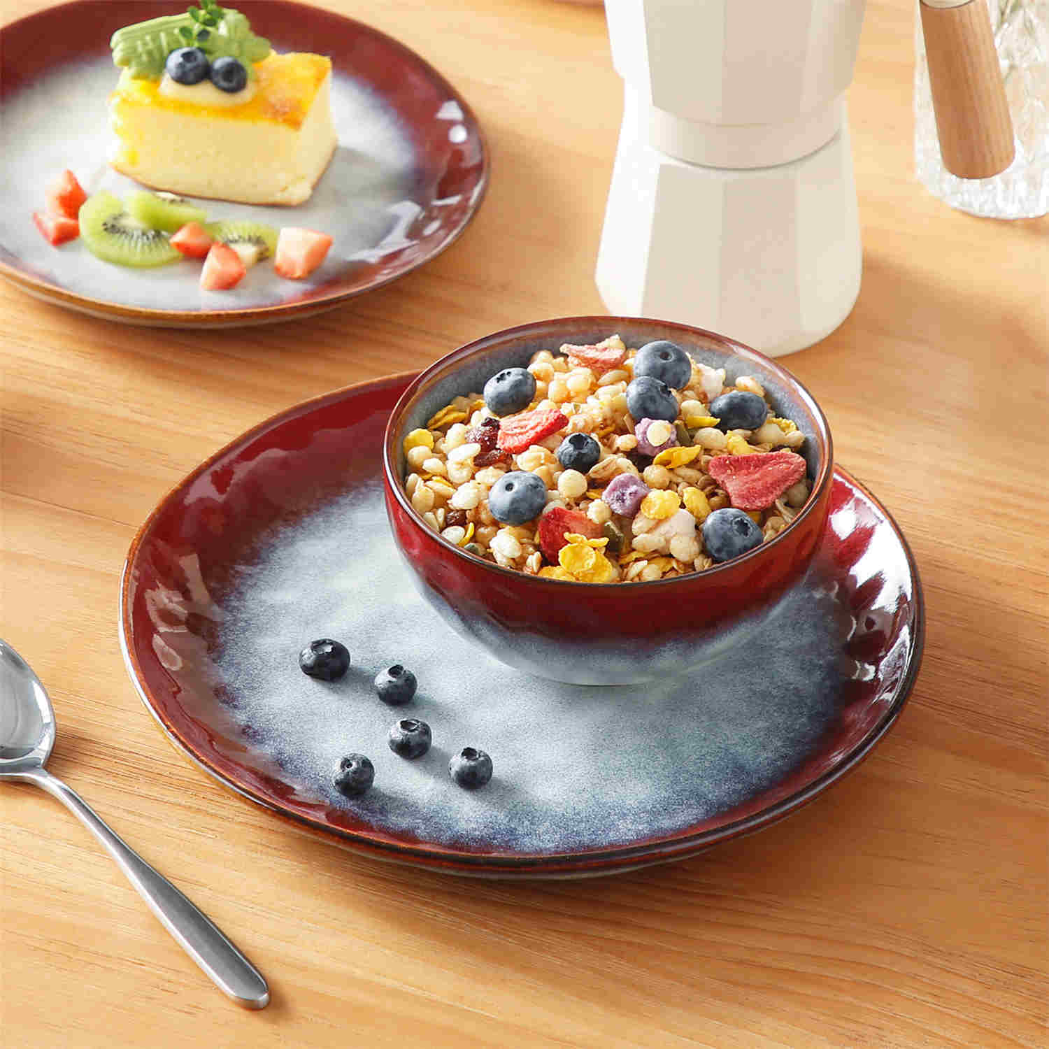 Starry 12-piece stoneware dinnerware set in red on a light wooden table - styled with lamb chops - pastries - coffee pot - and lemon water for a cozy farmhouse breakfast scene