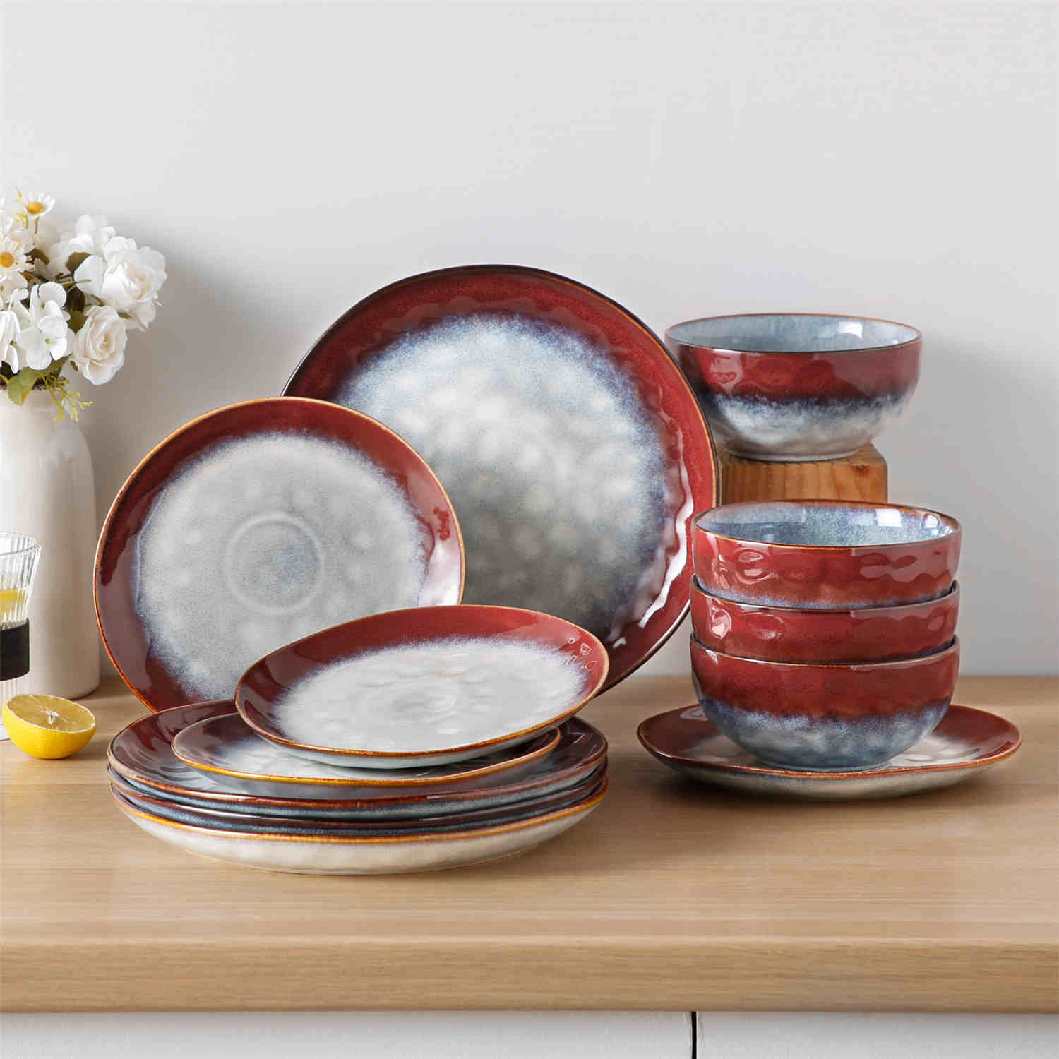 Starry 12-piece stoneware dinnerware set in red on a light wooden table - styled with lamb chops - pastries - coffee pot - and lemon water for a cozy farmhouse breakfast scene