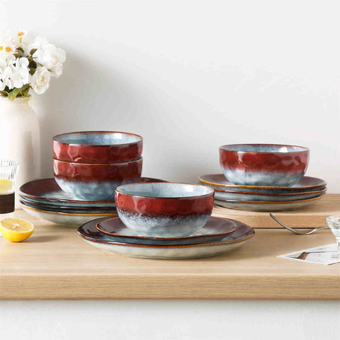 Starry 12-piece stoneware dinnerware set in red on a light wooden table - styled with lamb chops - pastries - coffee pot - and lemon water for a cozy farmhouse breakfast scene