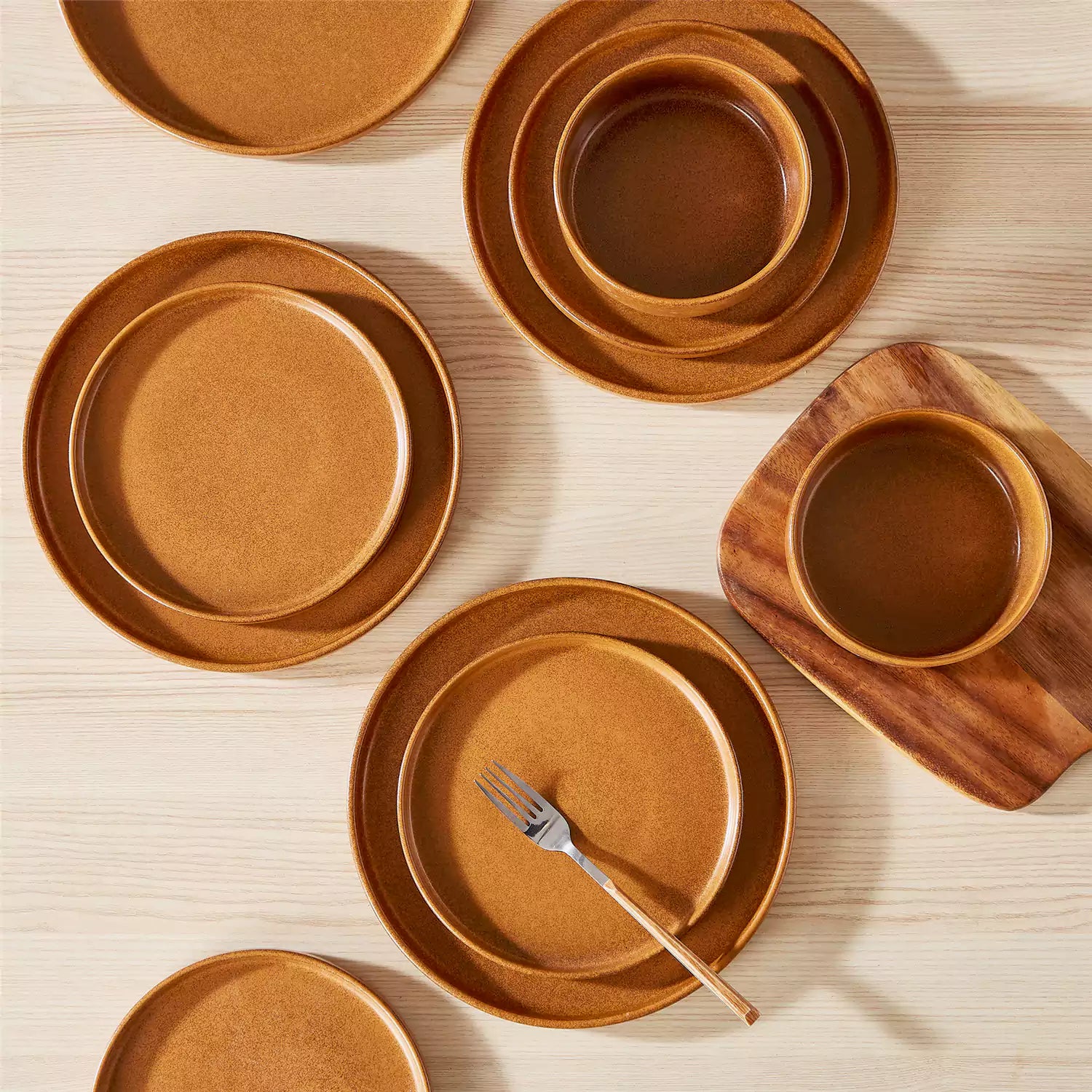 Caramel reactive glaze stoneware dinner plates styled with food on rustic wood table with woven placemats modern minimalist tableware set